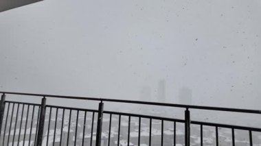 Kar, gökyüzünden yağarken şehirdeki binaları kaplıyor..