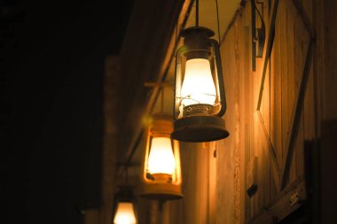 Fenerler ahşap bir duvara asılır, geceleri ışık saçar..
