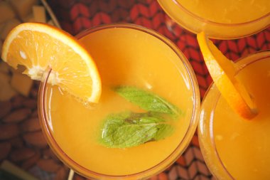 Üç fincan portakal suyu, nane yaprakları ve portakal dilimleri..