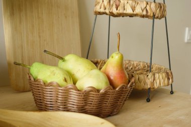 Kase bir masa yüzeyinde birkaç yeşil ve sarı armut barındırır..