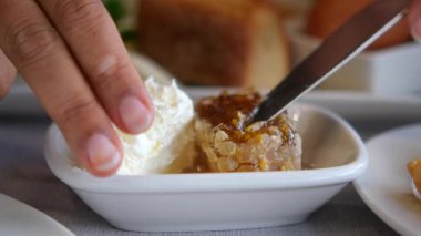 Bir insan kahvaltıda ekmeğe krema sürerek bal sürer..