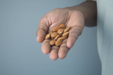Bir insan avucunda bir sürü badem tutar. Elin açık ten tonu vardır..