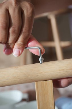Bir kişi ahşap bir ögeyi bir araç kullanarak ve parçaları birleştirerek birleştiriyor.