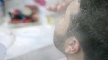 Bir adam bakım istasyonunda ürününü yüzüne sürüyor..