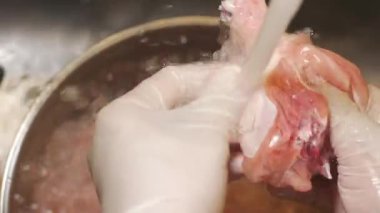 Mutfak lavabosunda akan suyun altında elleri yıkamak ve tavukları temizlemek..