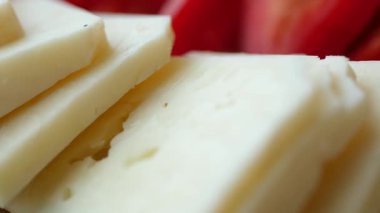 Tabaktaki taze domateslerin yanına yerleştirilmiş peynirleri izlemenin tadını çıkar..