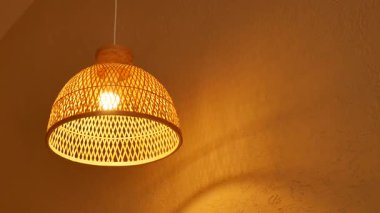 Ilık ışık, basit bir iç mekânda, örülmüş bir lambanın içinden parlar..