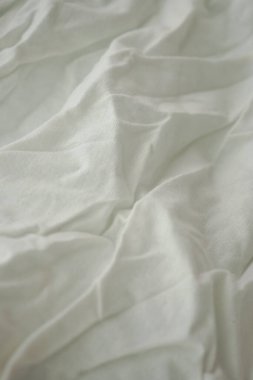 Beyaz kumaş düz bir yüzeyde kırışıklıklar ve kıvrımlarla yatar..