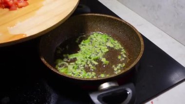 Doğranmış yeşil soğanlar ocakta tavada pişiriliyor..