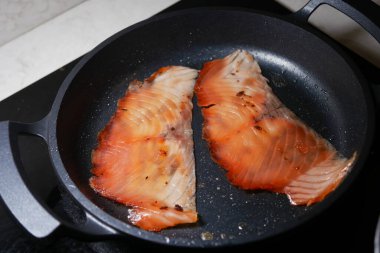 Sobanın tepesinde tavada iki somon fileto kızarıyor..