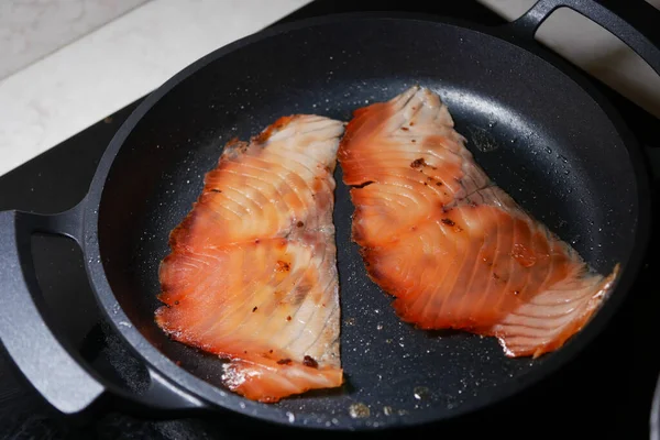 Sobanın tepesinde tavada iki somon fileto kızarıyor..