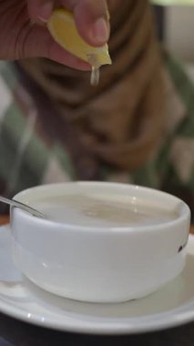 Birisi lezzet için bir kase çorbaya limon sıkıyor..