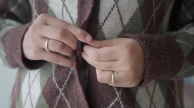 Sabahları evde bir hırkanın düğmelerini ilikliyor..