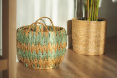 İyi aydınlatılmış bir odanın penceresinin yanında örülmüş bir sepet duruyor..