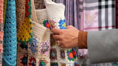 Markette renkli tığ işi eşyalar incelenir..