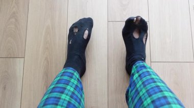 Ahşap bir zeminde otururken çorapları delik deşik eden biri..