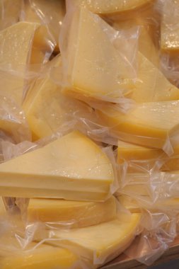 Sliced cheese is arranged neatly and wrapped in plastic on a table.