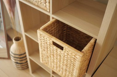 Ahşap bir raf dokuma sepetleri bitkilerle dolu bir odada tutar..