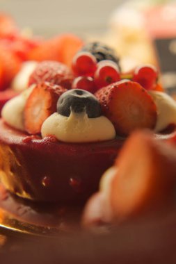 Renkli bir tatlıda turta üzerinde çilek, yabanmersini ve krema bulunur..