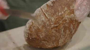 Bir fırıncı mutfakta bir somun ekmek şekillendirir ve hazırlar.