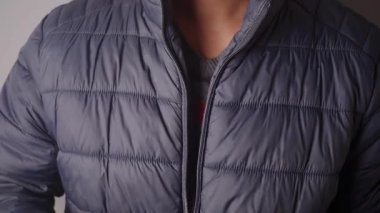 Stüdyo ortamında duran kişi ceketini ayarlar..