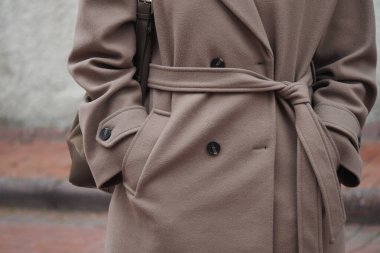 Bir insan elleri dışarıda bir sokakta kahverengi bir ceketin cebinde durur..