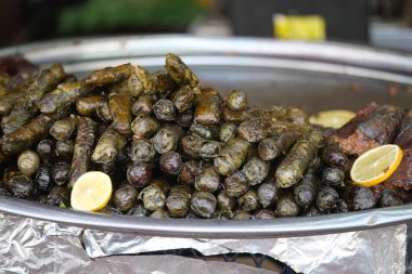 Bir yiyecek satıcısı markette içi pirinç ve otlarla dolu üzüm yaprakları hazırlar..
