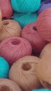 Pembe, turuncu ve mavi tonlarında iplik toplarının yakın plan görüntüsü.