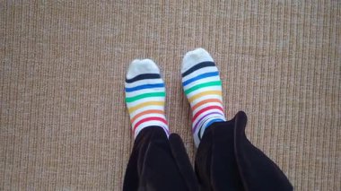 Halıda renkli çizgili çoraplar giyen bir insan.