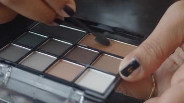 Eller fırçalı bir göz falı paleti kullanarak makyaj yapar..