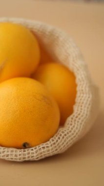 Portakallar basit bir arkaplana yerleştirilmiş bir ağ torbasında otururlar..