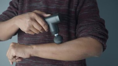 Kas gerilimini azaltmak için bir insan koluna masaj aleti uygular..