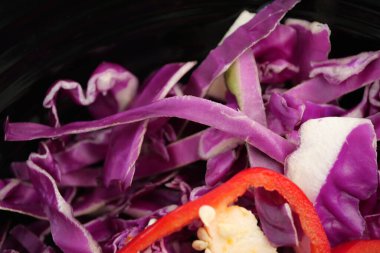 Parçalanmış mor lahana ve kırmızı biber siyah bir kasede oturur..