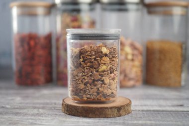 Granola, diğer kavanozlarla birlikte ahşap bir zeminde temiz bir kavanozda oturur..