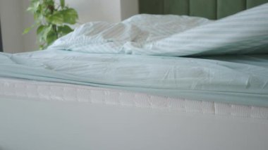 Temiz çarşaflar parlak bir yatak odası ortamında yatağın üzerine konur..