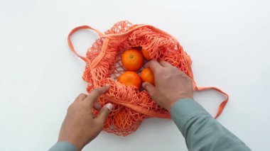 Eller portakallara uzanıyor. Masaya konmuş bir ağ torbasında..