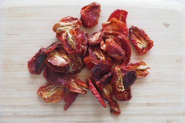 Kurutulmuş domatesler mutfaktaki tahta kesme tahtasına konur..