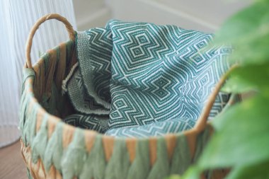 Katlanmış kumaşlı bir sepet yerde duruyor. Sıcak ve davetkar..