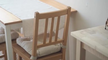 Basit bir oda düzeninde, tahta bir masanın yanında bir sandalye boş oturur..