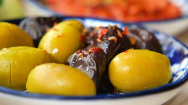 İnsanlar pazarda zeytin ve incir tadarken sosyalleşiyorlar ve gülümsüyorlar..