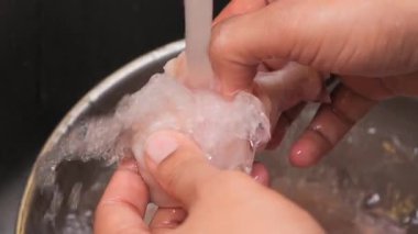 Mutfak lavabosunda akan suyla tavuk temizlemek..