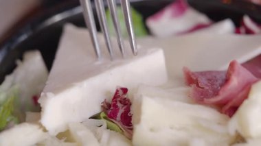 Yerel bir markette peynirli salata yiyen biri..