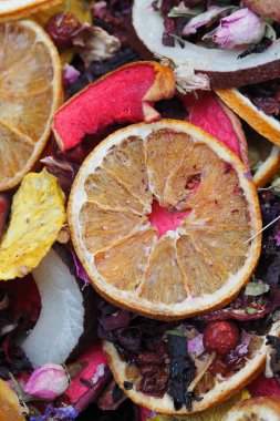 Kurutulmuş meyve dilimleri bir yüzey üzerinde bitki ve çiçeklerle karıştırılmış..