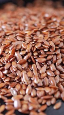 İnsanlar pazarda üst üste yığılmış keten tohumlarına bakarlar.