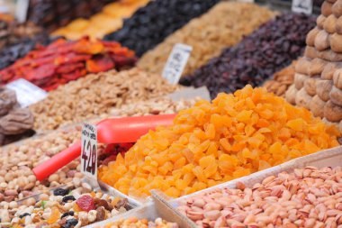 Tedarikçiler işlek bir pazarda çeşitli kurutulmuş meyve ve fındıklar düzenlerler..