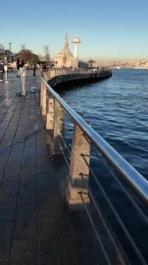 İnsanlar kıyıya yakın sularda gezinir ve şehrin manzarasının tadını çıkarırlar..