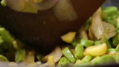 Bir insan mutfakta yeşil sebze ve soğan doğruyor..