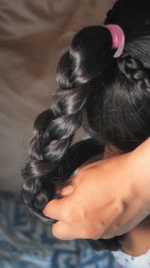 Kapalı bir ortamda bir insan saçını örüyor..