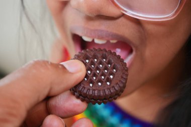 Bir çocuk, bir yetişkinin sunduğu kurabiyeye uzanır..