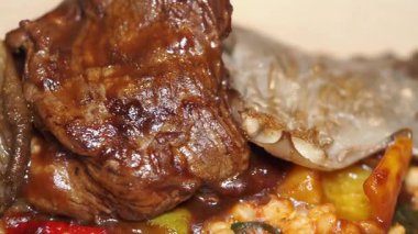 Biftek tabağı ve renkli sebzeler tabakta zengin bir sosla servis edilir..